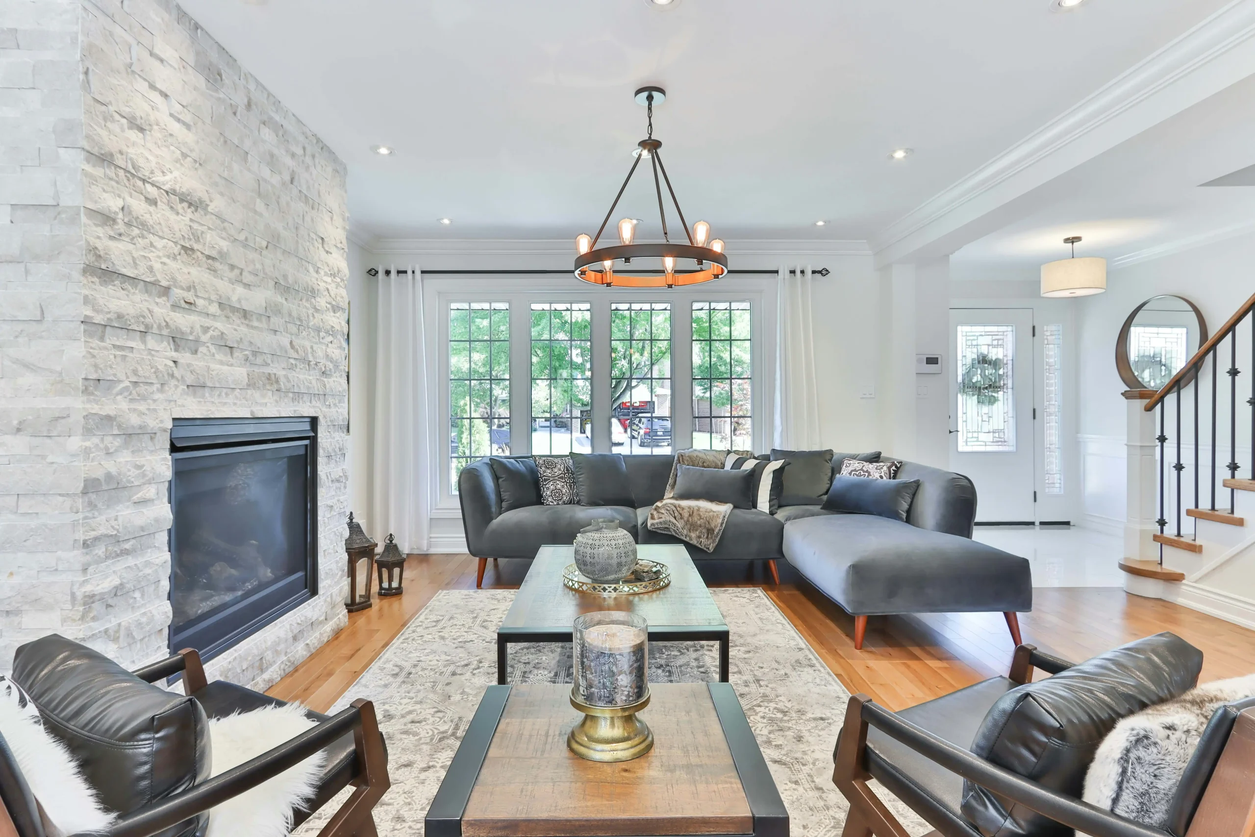 Living room with fireplace, beautiful couches, and on the back is the stairs to second floor